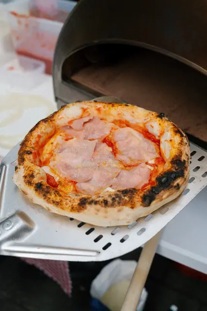 Čerstvě upečená pizza na lopatě u pece