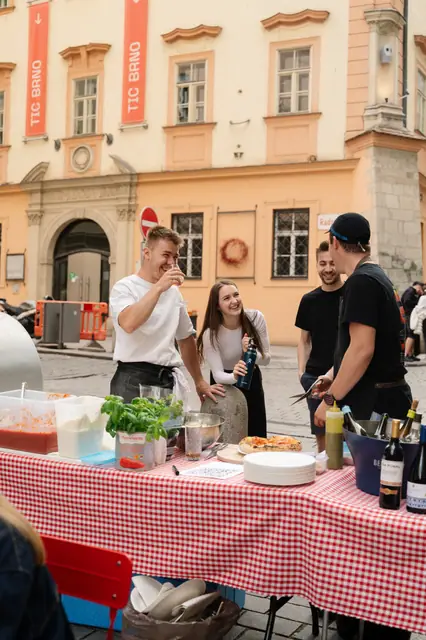 Stánek DAMO PIZZA s kostkovaným ubrusem v historickém centru Brna, pizzaioli a hosté
