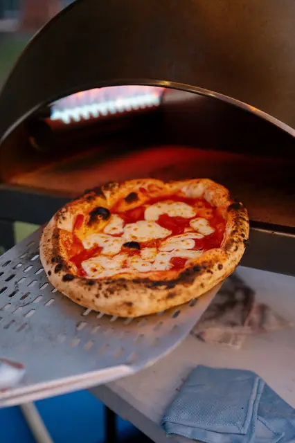 Upečená Margherita na lopatě u ústí rozpálené pece